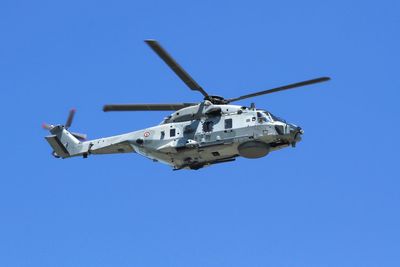 Low angle view of airplane flying against clear blue sky