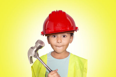 Portrait of cute boy holding camera over yellow background