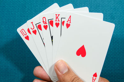 Close-up of hand holding red cards at table