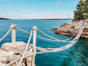 Old wooden rope bridge. foot bridge over water, sea, summer.