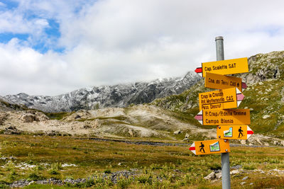 Road sign by mountain against sky