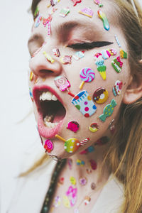 Woman with stickers on face screaming in front of white background