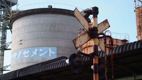 Low angle view of rusty railway signal against industry