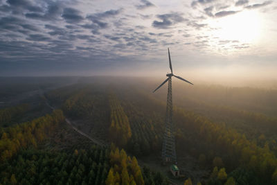 One wind turbine with a fixed propeller in a wooded area. windless weather on a foggy morning.