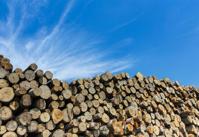 Stack of logs against blue sky
