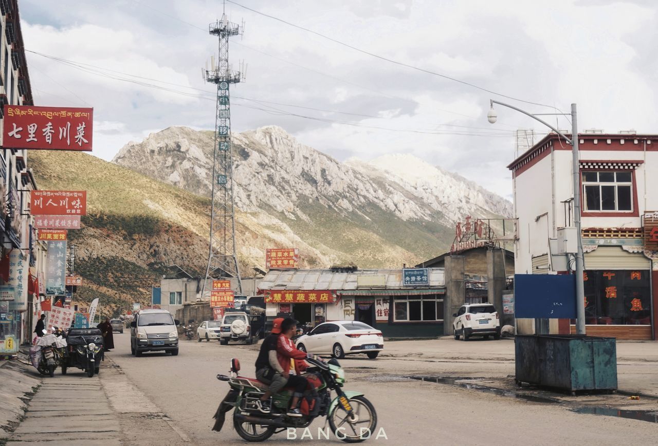 BICYCLES ON ROAD BY BUILDINGS AGAINST SKY