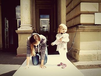 Mother and daughter sitting on floor in city