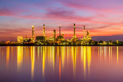 Illuminated factory against sky at sunset