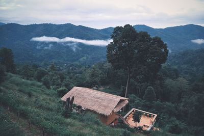 House amidst trees and mountains against sky