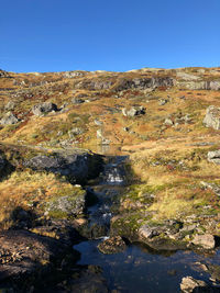 Rock formations on landscape against clear blue sky