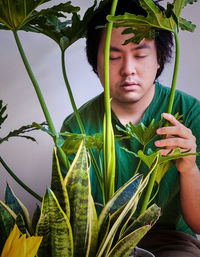 Portrait of young man with plants indoors.