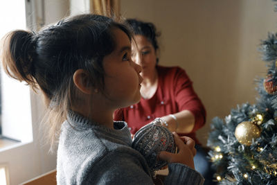 Portrait of young woman looking away while sitting on table at home