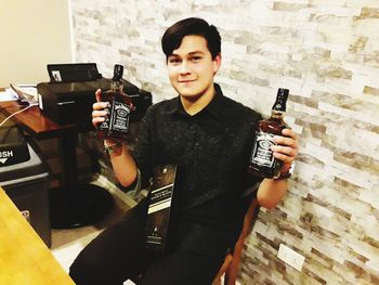 Young man holding bottle while standing at bar