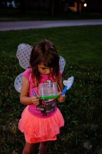 Cute girl holding toys while standing on field