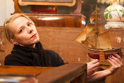 Portrait of woman with antique boat figurine in store