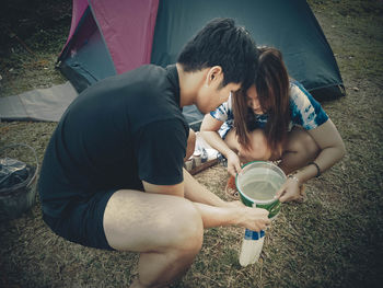 Friends filling plastic bag with water on field