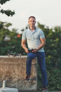 Portrait of man operating drone against sky