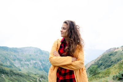 Young woman standing against mountain