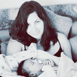 Portrait of smiling mother with sleeping baby boy at home