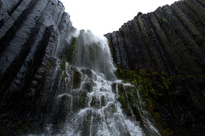 Low angle view of waterfall against sky
