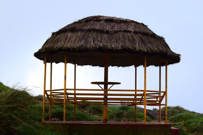 Gazebo with thatched roof against clear sky