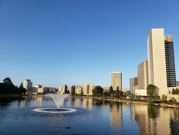 Lake and buildings against clear sky