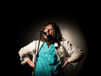 Man with arms raised standing against black background