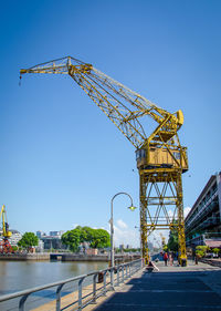 Yellow crane on pier at puerto madero against clear sky