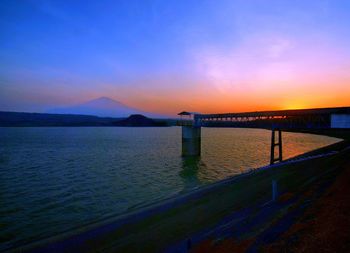 Bridge over sea against sky during sunset