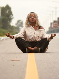 Portrait of young woman sitting on road