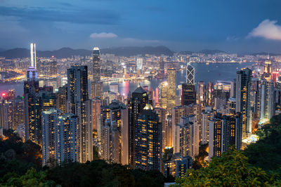 Aerial view of illuminated modern buildings in city against sky at dusk