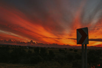 Road sign against orange sky
