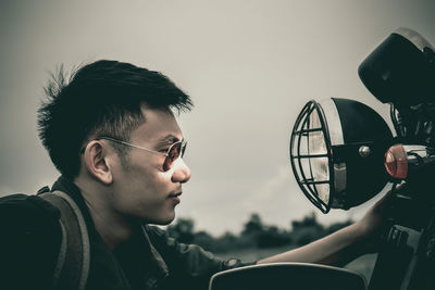 Side view of young man looking at headlight of motorcycle