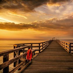 Pier in baltic sea against cloudy sky during sunset
