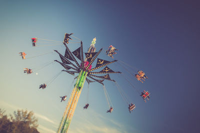 Low angle view of chain swing ride against sky