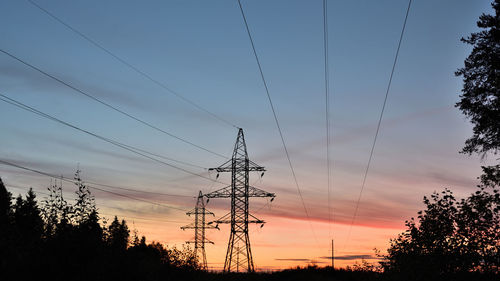 Low angle view of silhouette electricity pylon against sky during sunset