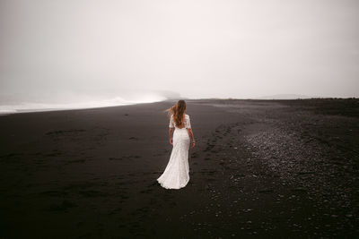 Woman standing on beach against sky