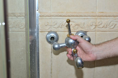 Close-up of hand holding faucet against door