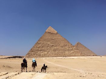 Group of people on desert against clear sky