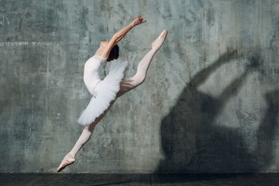 Woman dancing against gray wall