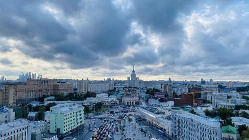 High angle view of city buildings against cloudy sky