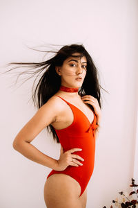 Beautiful young woman standing against wall