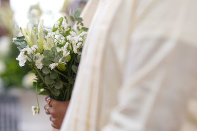 Midsection of bride holding bouquet