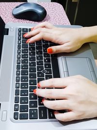 Cropped hands of woman using laptop on table