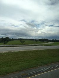 Scenic view of grassy field against cloudy sky