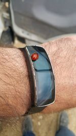 Close-up of ladybug on smart watch worn by man