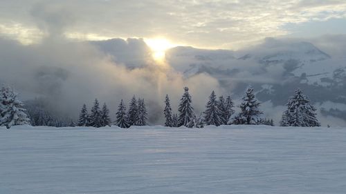 Scenic view of snowcapped landscape in foggy weather during sunset