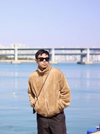 Young man standing against river