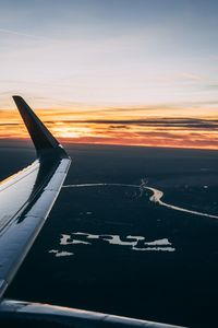 Airplane flying over sea against sky during sunset