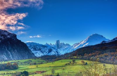 Scenic view of field and mountains against blue sky